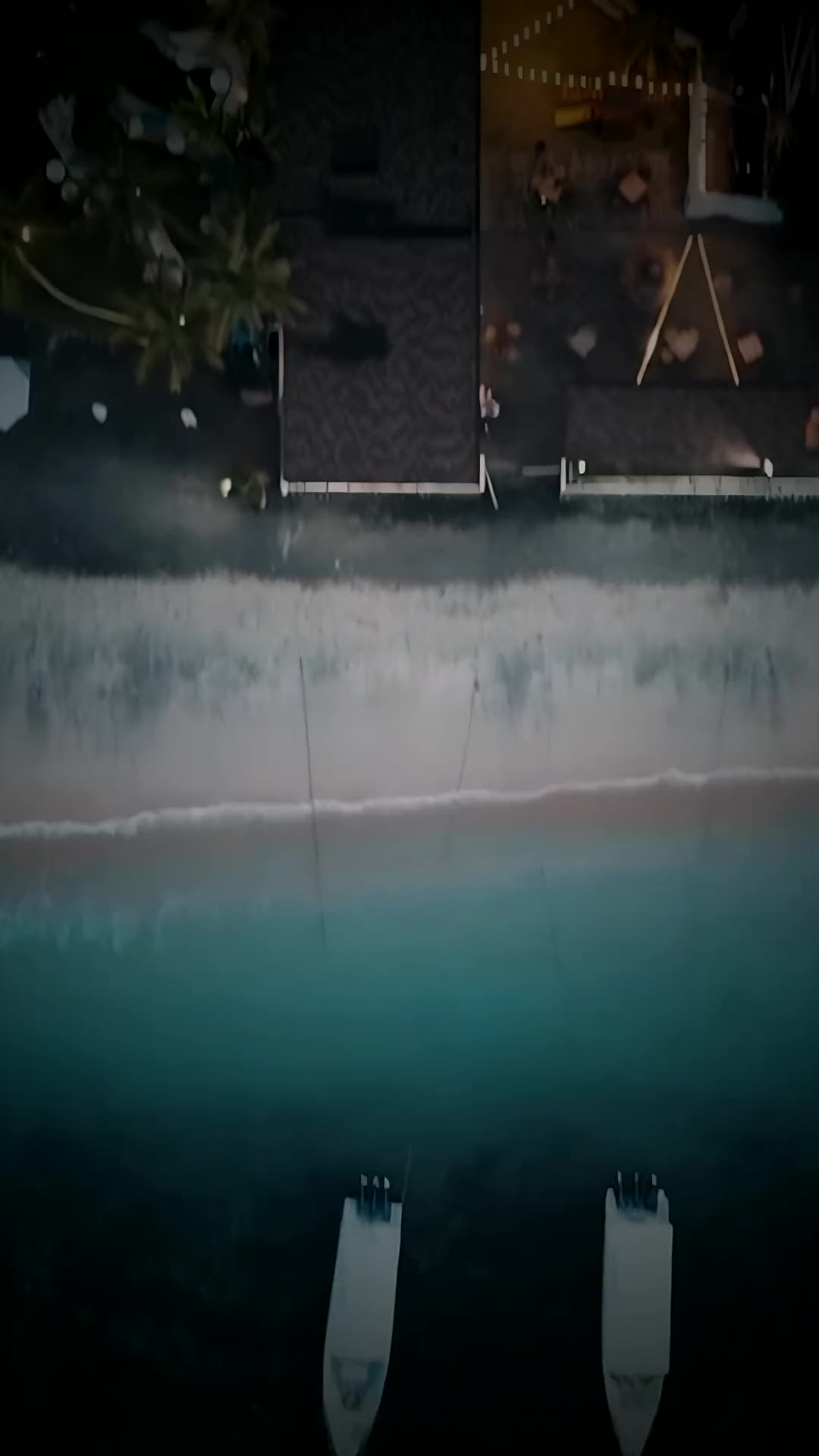 Aerial view of Plaza Marietta at dusk: thatched roofs, string lights, the sand and the sea